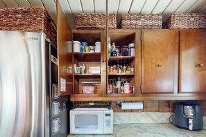 Une cuisine de taille réduite, dotée d’un réfrigérateur en acier inoxydable, d’un four à micro-ondes et d’armoires en bois situées en hauteur.