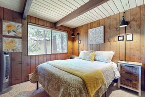 Ein Schlafzimmer mit einem großen Bett, Holzwänden, einem Fenster und einem Heizgerät.