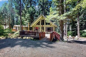A cabin with a wooden deck, surrounded by trees. - Vintage 1BR + loft  cabin with fireplace (Ronald)