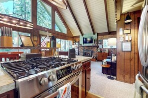 Eine moderne Küche mit einem großen Gaskochfeld, Holzschränken und einem Kamin aus Stein.