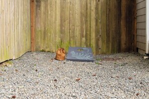 A wooden fence, a brown bag, and a grey object with a leaf design on a gravel surface. - 3 BR home in Port Angeles with private sauna (Port Angeles)