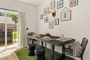 A dining area with a table set for four, a sliding glass door leading to an outdoor space, and a wall adorned with framed artwork. - 3 BR home in Port Angeles with private sauna (Port Angeles)