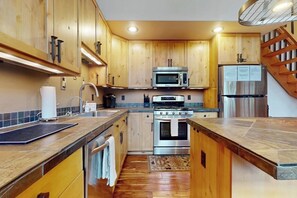 A kitchen with wooden cabinets, stainless steel appliances, and a tiled backsplash. - 3 BR beautiful home with hot tub and work space (Ronald)