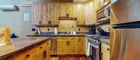 Una cocina con gabinetes de madera, un refrigerador de acero inoxidable y una estufa a gas.