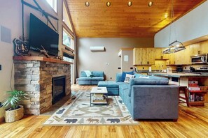 Ein Wohnzimmer mit Kamin aus Stein, einem an der Wand befestigten Fernseher und einem Sofa.