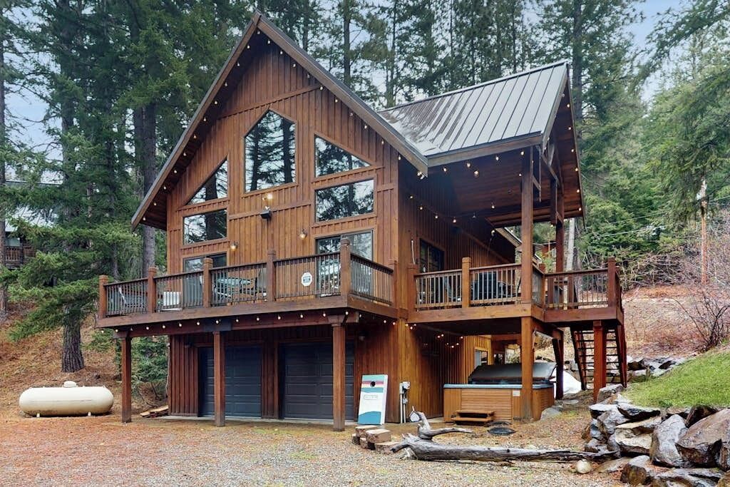 Eine zweistöckige Holzhütte mit Balkon, Garage und Whirlpool.