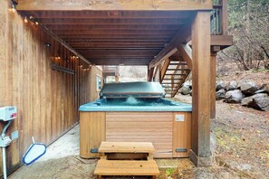 A wooden outdoor hot tub with a built-in bench, surrounded by a wooden deck and a covered area. - 3 BR beautiful home with hot tub and work space (Ronald)