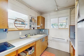 Eine Küche mit weißen Schränken, einer Holz Arbeitsplatte, einem Spülbecken und einem Fenster mit Blick auf ein Haus.