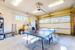 A spacious indoor area with a ping pong table, a ladder, and a shelving unit. - 3BR mtn-view home with firepit, grill, Ping-Pong (Cle Elum)