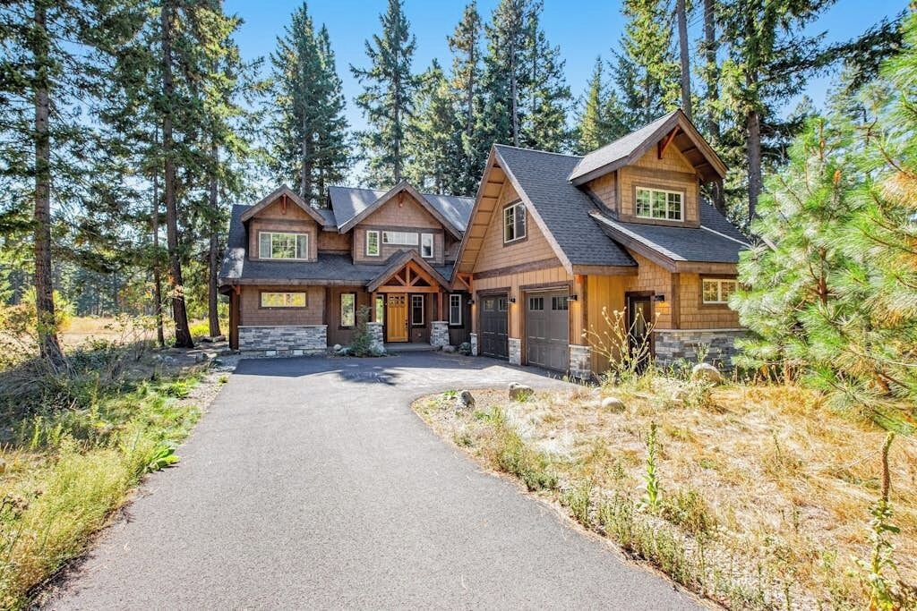 A multi-story log cabin with a stone foundation, surrounded by a forest.