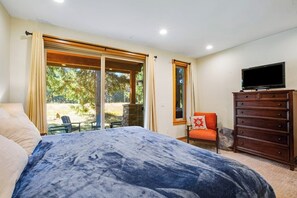 A bedroom with a large bed, a dresser, a television, and a sliding glass door leading to an outdoor area. - Dog-friendly 4BR with hot tub, game room & patio (Cle Elum)