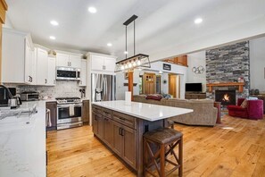 Cozinha moderna com ilha central, eletrodomésticos embutidos e parede decorada com pedra.