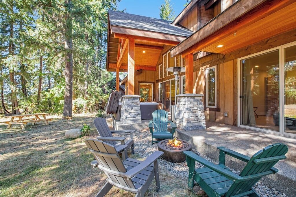 Une cabane en bois avec une cheminée en pierre, un espace salon extérieur et un patio couvert.