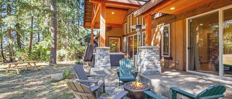 Une cabane en bois avec une cheminée en pierre, un espace salon extérieur et un patio couvert.