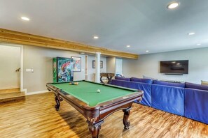A pool table in a room with a wooden floor, a blue sofa, and a television on the wall. - 4BR Bayview Dog Friendly - Balcony - Firepit (Brinnon)