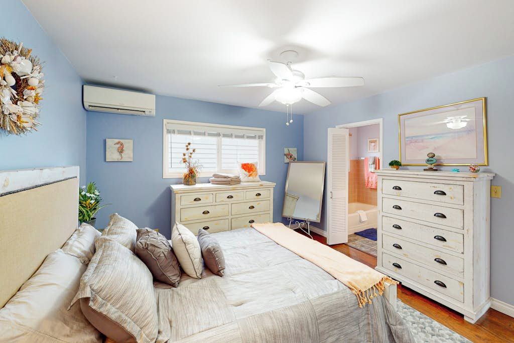Ein Schlafzimmer mit Bett, Kommode und Deckenventilator.