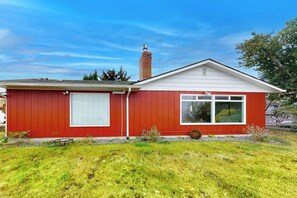 Een huis met één verdieping, een rode gevel, een schoorsteen en een kleine voortuin.
