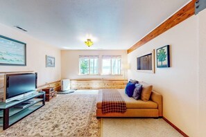 Ein gemütliches Wohnzimmer mit einer Couch, einem Flachbildfernseher und einem Holzbalken an der Decke.