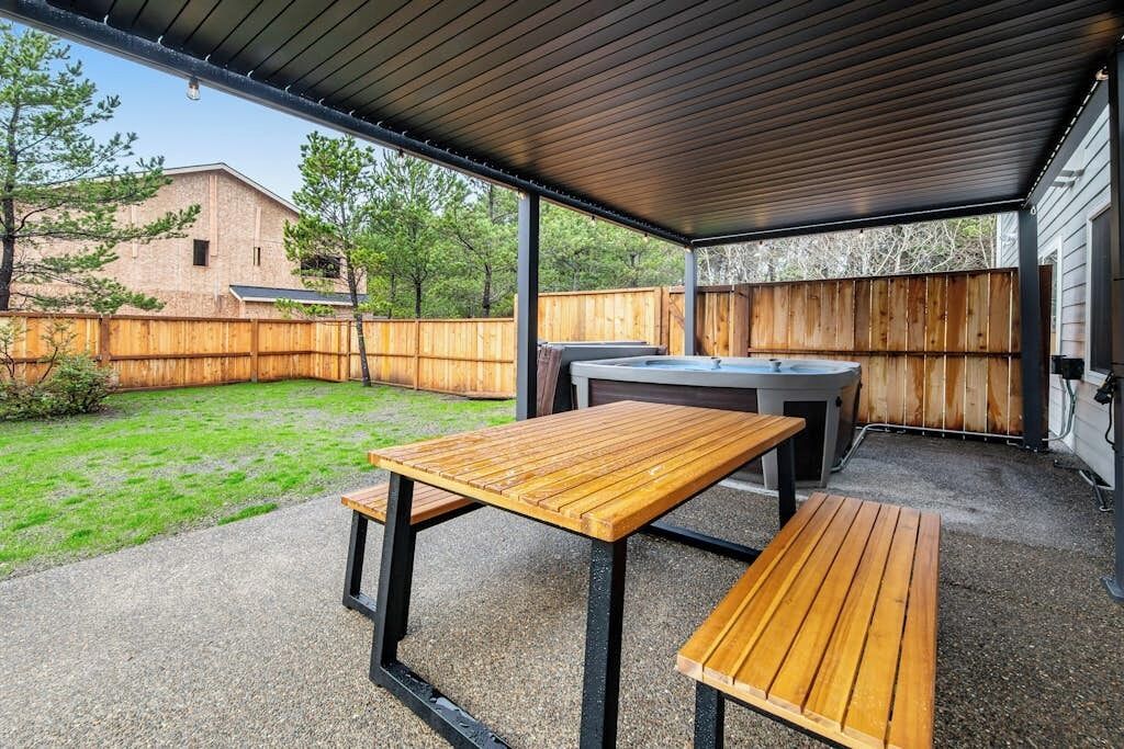 Une terrasse extérieure avec une table et des bancs, un barbecue et un espace abrité.