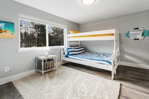 A child's bunk bed with a white frame, a small bedside table with a lamp, and a window with a view of trees. - Modern 3BR Dog Friendly - Hot Tub - Patio (Westport)