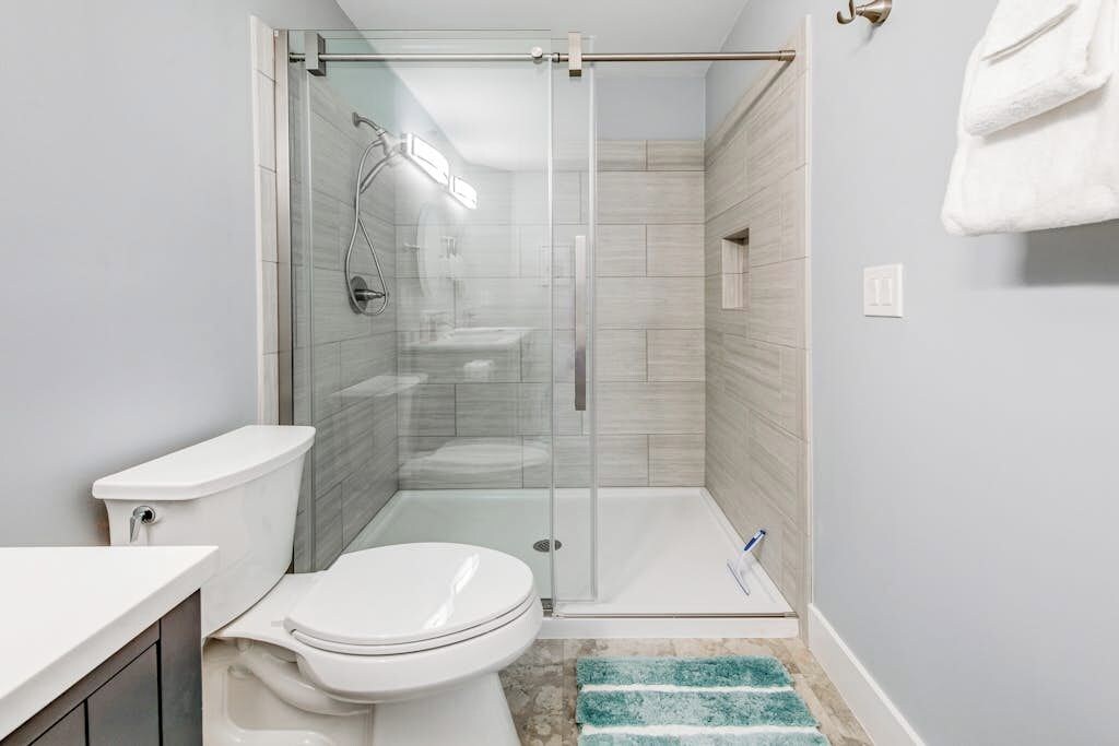 A modern bathroom with a glass-enclosed shower, a toilet, and a sink.