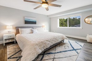 A bedroom with a bed, a nightstand, a ceiling fan, a window with a view, and a rug. - Modern 3BR Dog Friendly - Hot Tub - Patio (Westport)