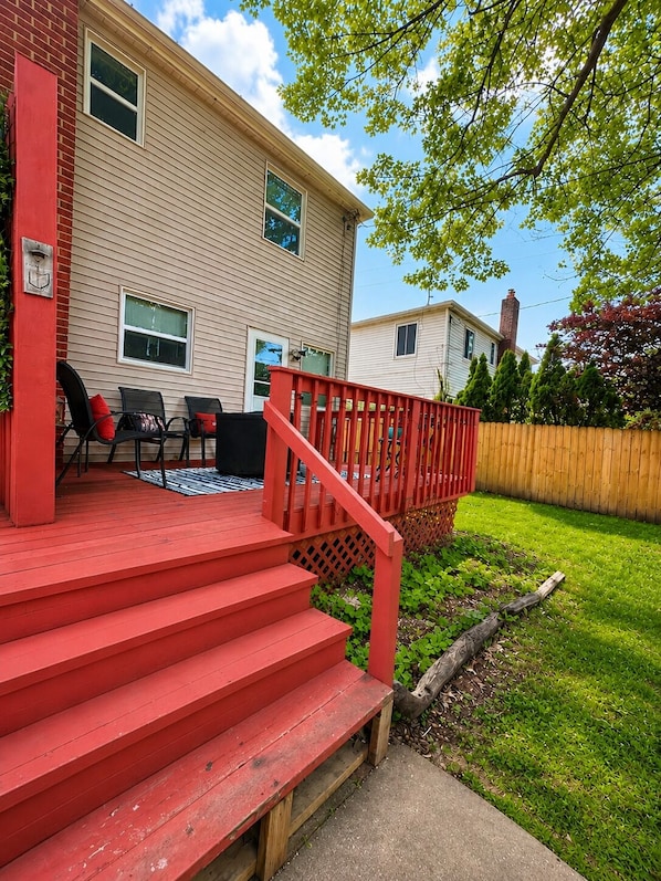 Une propriété résidentielle dotée d’une terrasse rouge, d’un mur en briques et d’une clôture en bois.