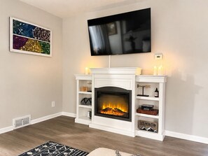 A living room with a fireplace, a mounted TV, and a framed artwork on the wall. - Modern Cozy Stay Near
Downtown, Blossom & Cuyahoga Valley National Park (Cuyahoga Falls)