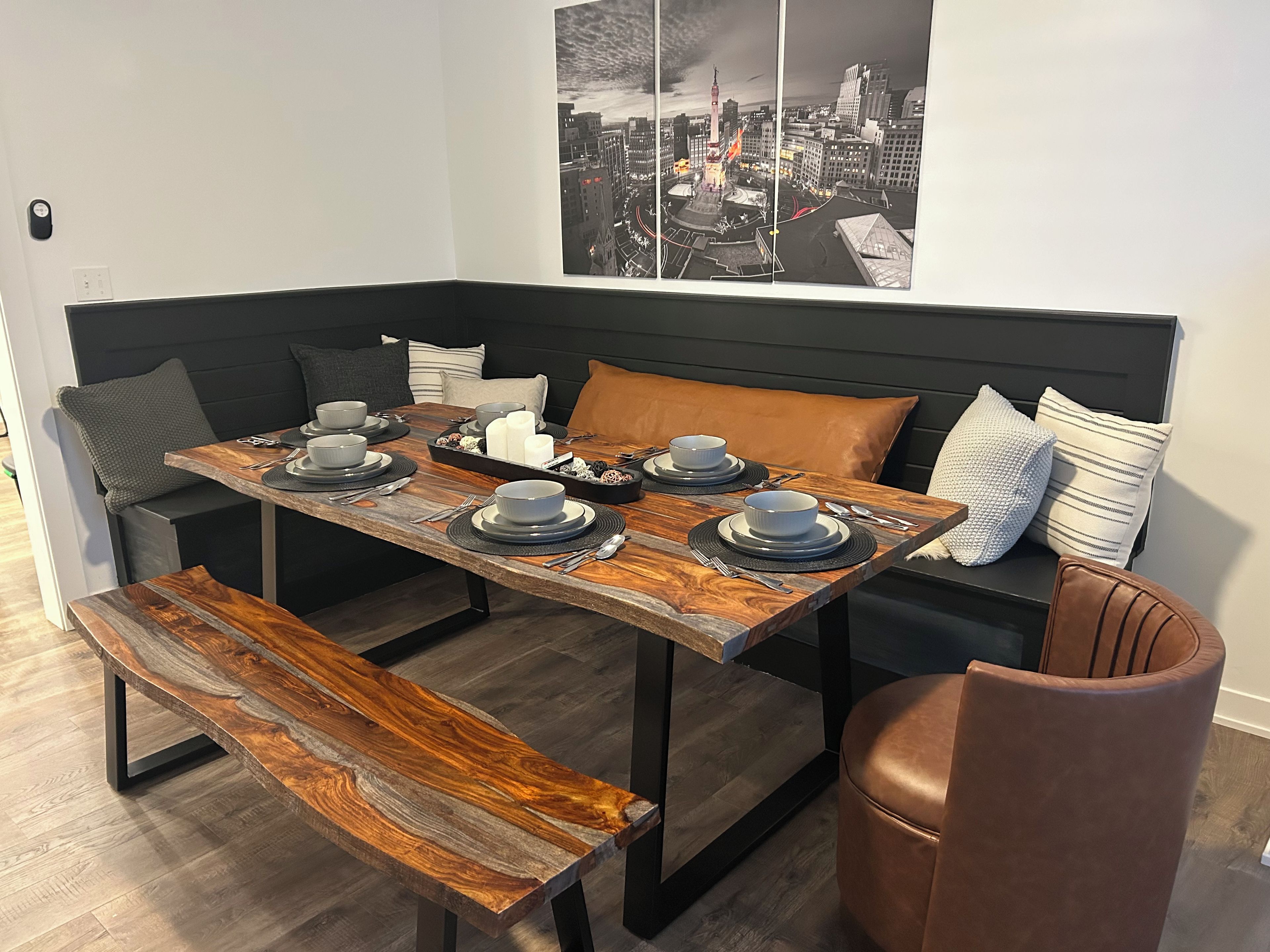 A dining area with a wooden table set for two, a bench, and a brown leather chair.