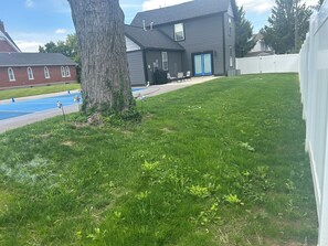 Ein Wohnhaus mit einem großen Baum, einer blauen Garagentür und einem weißen Zaun.