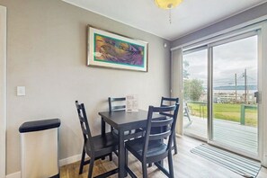 A dining area with a table and chairs, a framed artwork on the wall, and a view through a glass door. - 3BR Waterview - Deck - Washer Dryer (Des Moines)