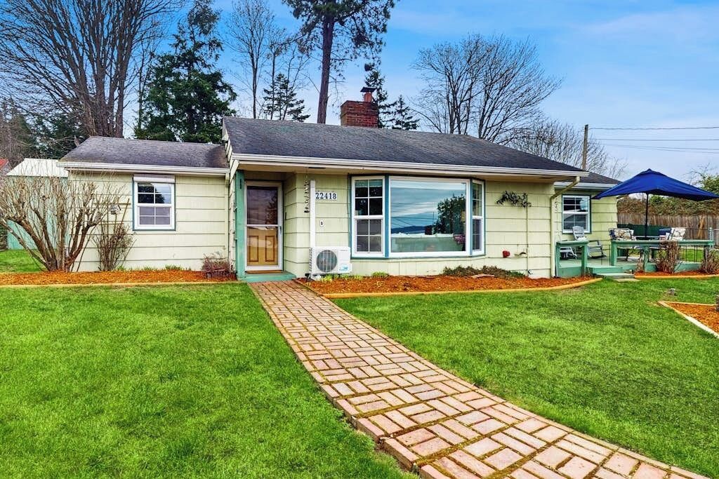 Une maison de plain-pied avec un chemin en briques menant à la porte d’entrée.
