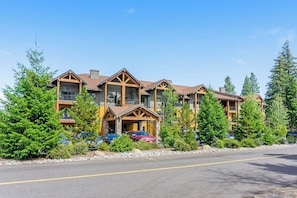 A multi-story lodge with a prominent entrance, balconies, and a parking area with cars. - Elegant 2BR Golf Course View Suncadia Resort Dog (Cle Elum)