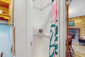 Ein Badezimmer mit Dusche, Handtuchhalter und Ablage für Pflegeprodukte.