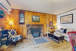 Ein Wohnzimmer mit Kamin, Holzwänden, einer Couch, einem Couchtisch und einer Lampe.