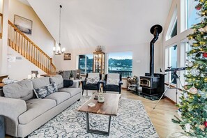 Ein geräumiges Wohnzimmer mit einer Couch, Sesseln, einem Couchtisch, einem Kamin und einem Weihnachtsbaum.