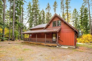 Eine Hütte mit Veranda, umgeben von hohen Bäumen.