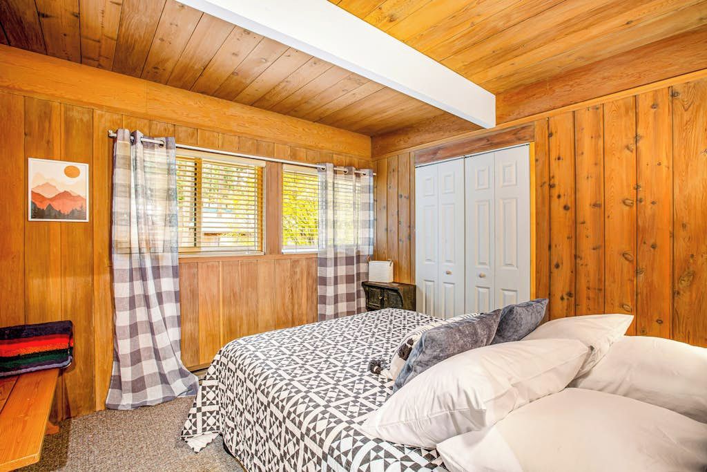 Un dormitorio con cama, cortinas, ventana y puerta.