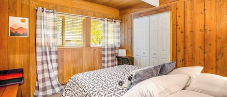 Un dormitorio con cama, cortinas, ventana y puerta.
