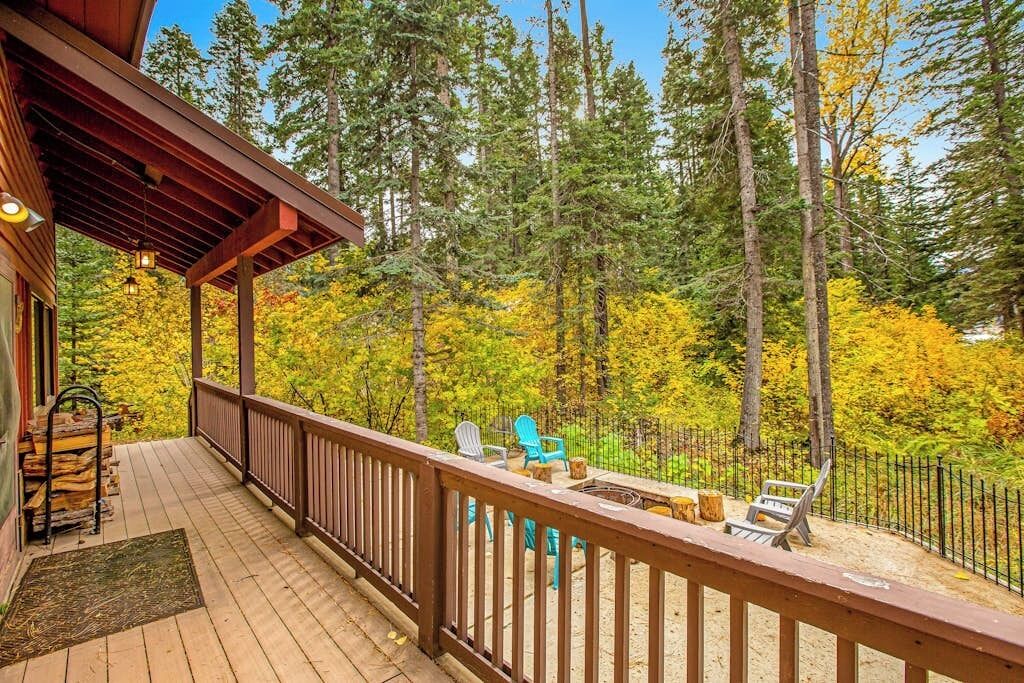 A wooden deck with outdoor seating and a view of a forest.