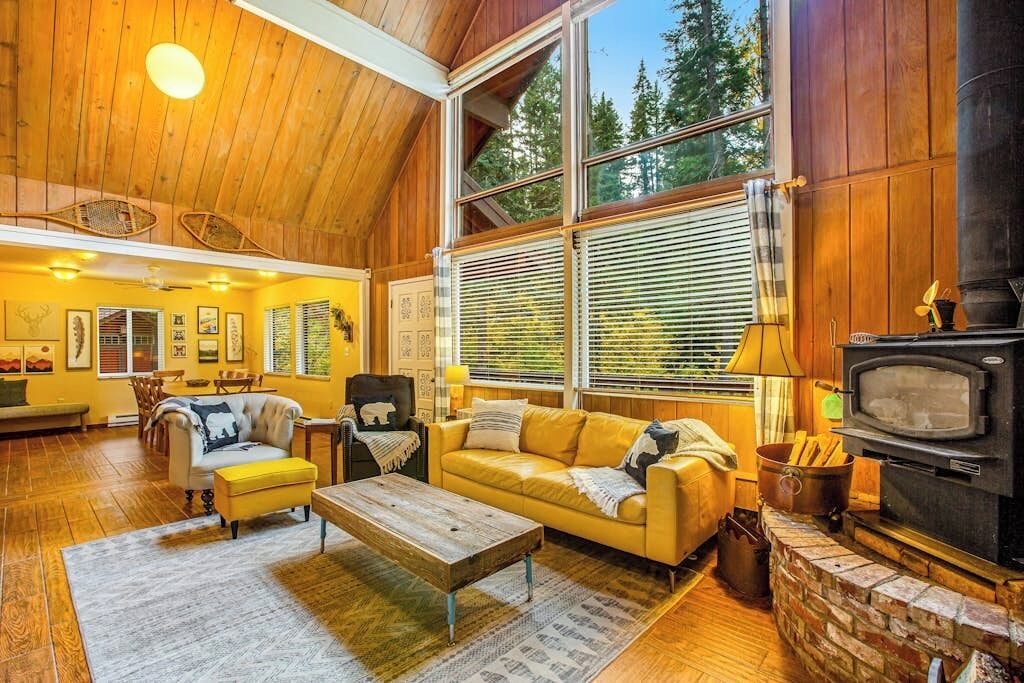 Una sala de estar acogedora con chimenea, pisos de madera y ventanas amplias.