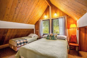 Een kamer met twee bedden, een houten plafond en een raam met gordijnen.