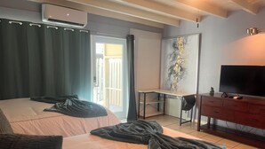 Et hotelværelse med to senge, et skrivebord, en fjernsyn og en balkon.