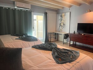 Una camera d'albergo con due letti, una scrivania, una televisione e un balcone.