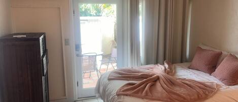 A bedroom with a bed, a wooden cabinet, a sliding glass door leading to a patio, and an air conditioning unit.