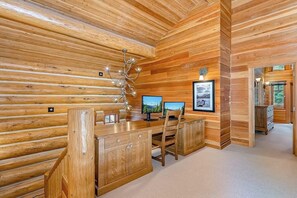 A wooden interior with a desk, two monitors, and a chandelier. - Mountain 4BR with hot tub, game room & fireplaces (Snoqualmie Pass)