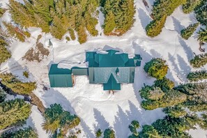 Luchtbeeld van een met sneeuw bedekte constructie, omringd door bomen.
