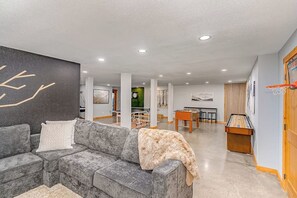 A modern living room with a gray sectional sofa, a pool table, and a billiards table. - Mountain 4BR with hot tub, game room & fireplaces (Snoqualmie Pass)