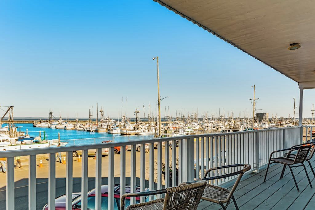 A marina with boats docked, a covered deck with chairs, and a clear sky.