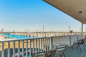 Ein Yachthafen mit vertäuten Booten, eine überdachte Terrasse mit Stühlen und ein klarer Himmel.